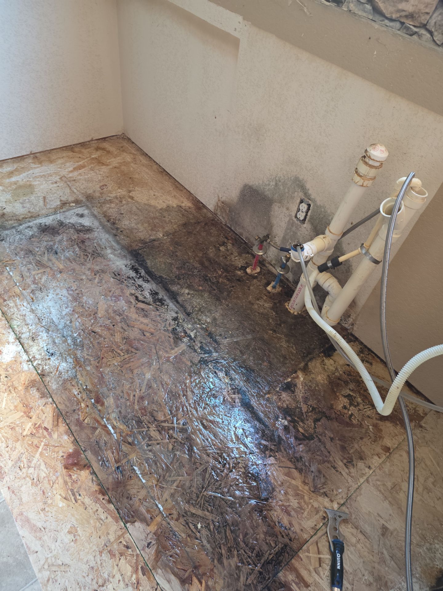 A picture of staining on the subfloor beneath a kitchen sink after the cabinet was removed.